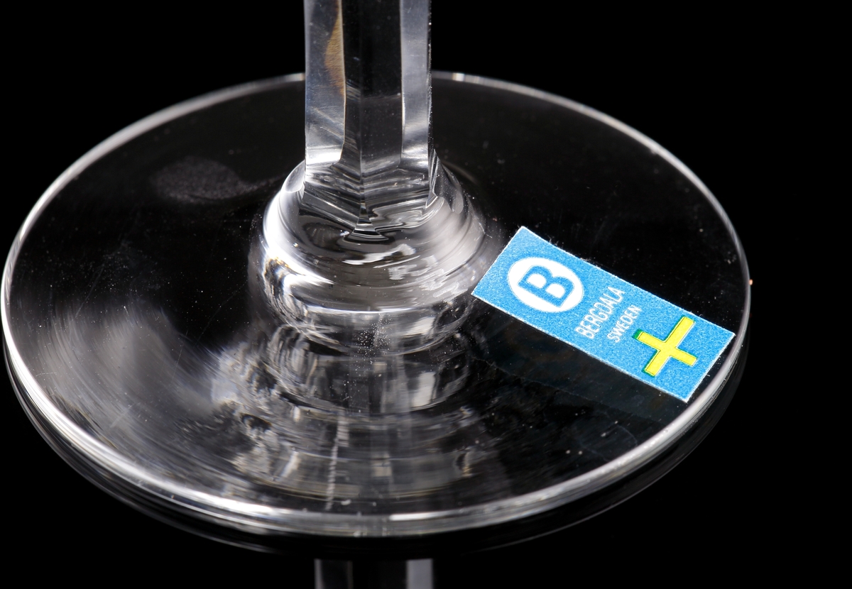 Rundad kupa med tre slipade blommor. Facettslipat ben.
Kronbladen är schattérslipade och bladen är skärslipade.
Etikett: Rektangulär med blå botten. En vit ring med ett "B" texten "Bergdala Sweden", sam tsvenska flaggan.