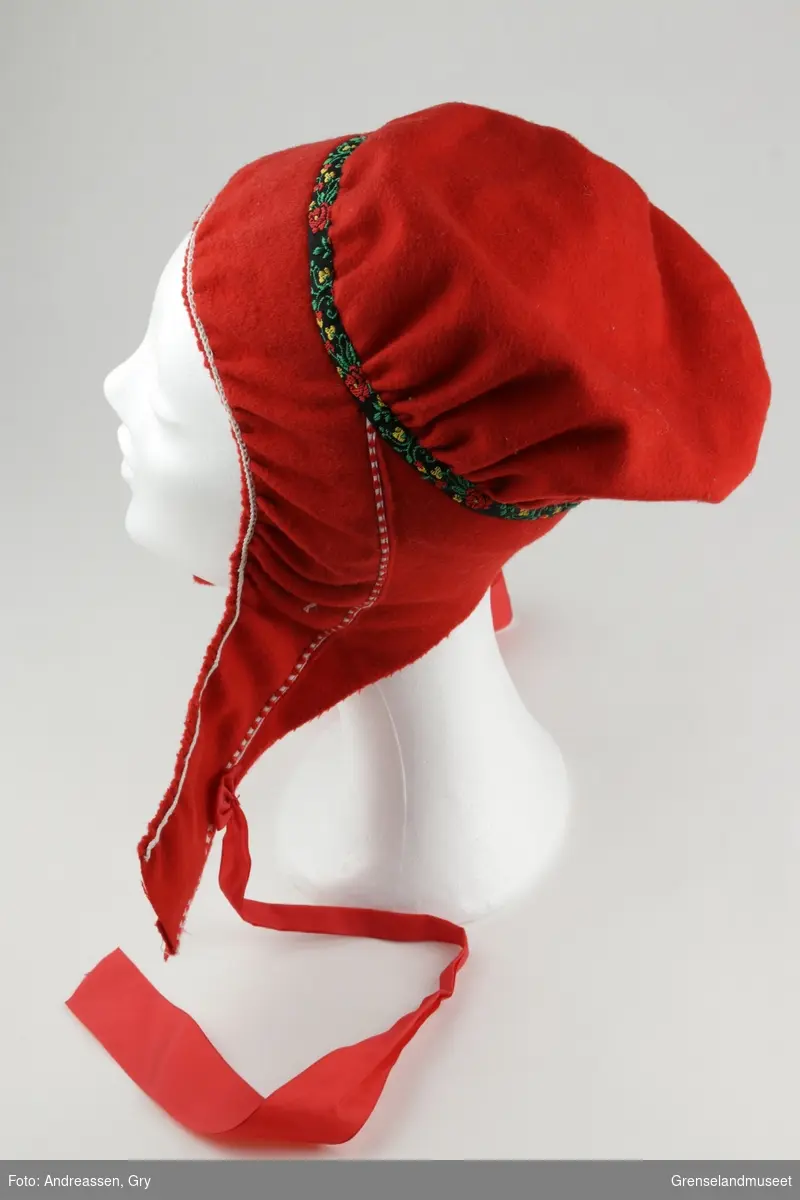Samisk kvinnelue. Rødt klede med pyntebånd.