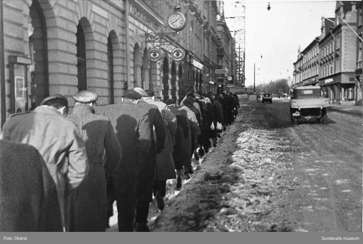 "Studentexamen 1937 vid Sundsvalls högre läroverk började med svensk skrivning. Innan vi gick till skolan samlades vi vid Bewe's hörna (Storgatan-Torggatan). Där släppte var och en av oss en ettöring från födelseåret ner i dagvattenbrunnen. Därefter gick vi till skolan med en fot i rännstenen och den andra på trottoaren så lång det gick." Bild 2 Fr v Lennart Uhlin, Ture Engblom och Martin Löfgren. Bild 6 Betygen studeras. Fr v Liljekvist, Curt Stål, L M Thuresson samt okänd. Bild 8 Numrerade personer. 1. okänd 2. L. H. Thuresson 3. okänd 4. Thure Engblom 5. okänd 6. Martin Löfgren 7. Lundgren (?) 8. Curt Stål 9. G-A Wahlsten 10. Ingemar Flodén 11. Anna-Lisa ? 12. Nilsson (lärare) 13. Maidi Budde 14. Lennart Uhlin 15. Harald Schibbye. 
Bilder ur fotoalbum som tillhört G A Wahlsten.