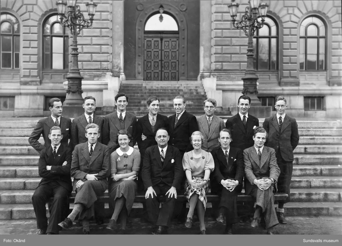 "Studentexamen 1937 vid Sundsvalls högre läroverk började med svensk skrivning. Innan vi gick till skolan samlades vi vid Bewe's hörna (Storgatan-Torggatan). Där släppte var och en av oss en ettöring från födelseåret ner i dagvattenbrunnen. Därefter gick vi till skolan med en fot i rännstenen och den andra på trottoaren så lång det gick." Bild 2 Fr v Lennart Uhlin, Ture Engblom och Martin Löfgren. Bild 6 Betygen studeras. Fr v Liljekvist, Curt Stål, L M Thuresson samt okänd. Bild 8 Numrerade personer. 1. okänd 2. L. H. Thuresson 3. okänd 4. Thure Engblom 5. okänd 6. Martin Löfgren 7. Lundgren (?) 8. Curt Stål 9. G-A Wahlsten 10. Ingemar Flodén 11. Anna-Lisa ? 12. Nilsson (lärare) 13. Maidi Budde 14. Lennart Uhlin 15. Harald Schibbye. 
Bilder ur fotoalbum som tillhört G A Wahlsten.