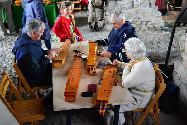 To menn og en dame som spiller Langeleik