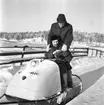 Paul Nes sitter och Rolf Möller står bakom på en snöskoter i ett mycket snörikt landskap.