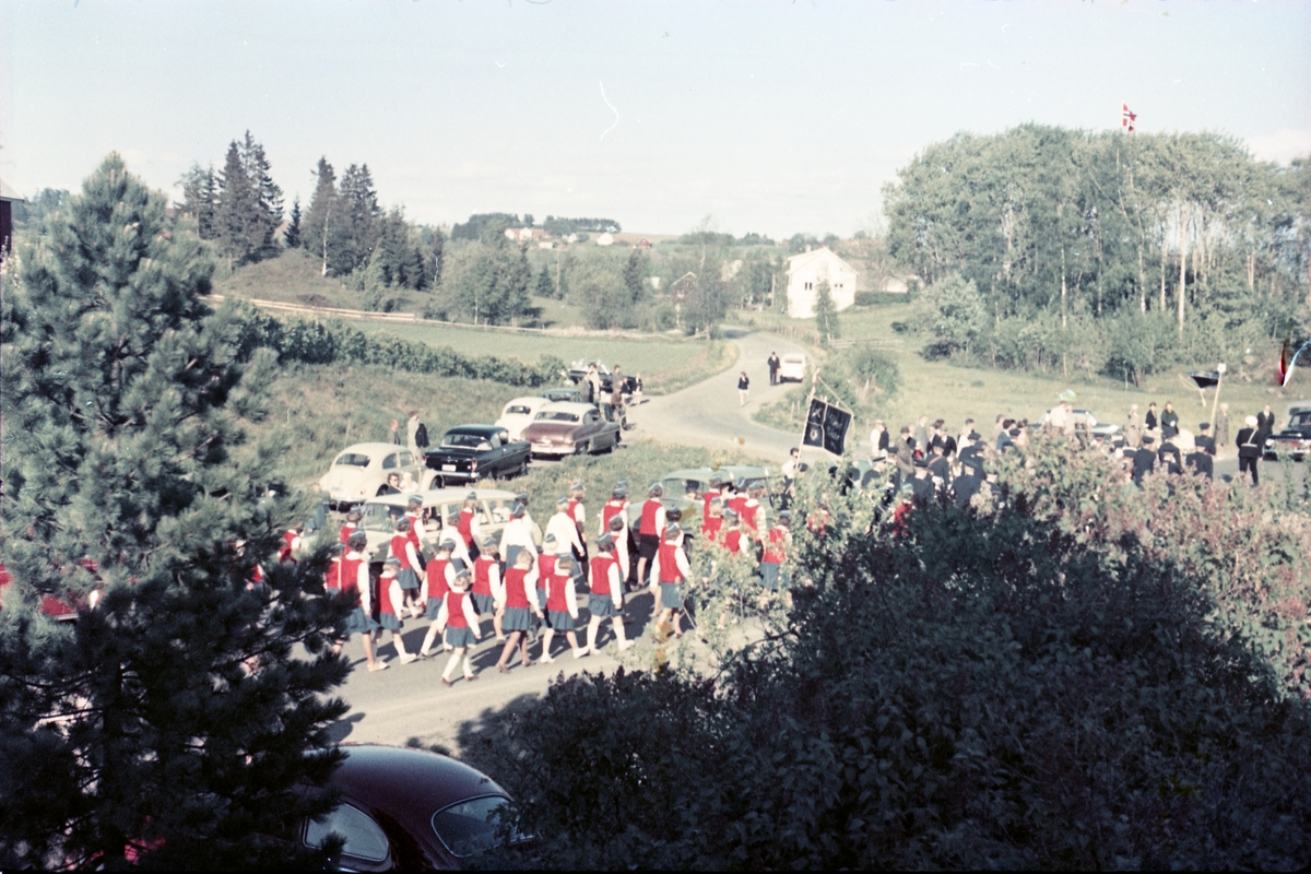 Serie på 16 bilder trolig fra Sangens og Musikkens Dag i Østre Toten, muligens 1961. Bildene er tatt i retning Brunsberg fra fotografens eiendom Odberg på Kraby, der forskjellige korps og kor deffilerer forbi.