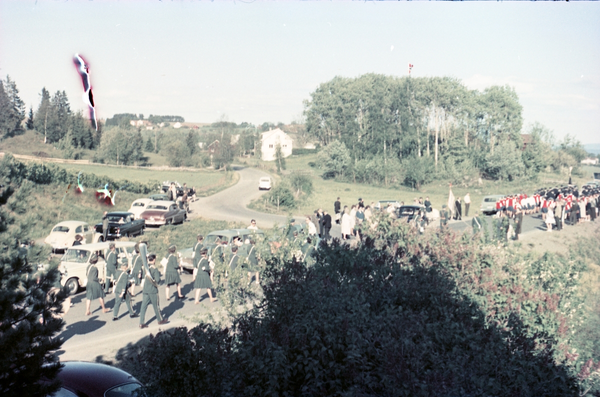 Serie på 16 bilder trolig fra Sangens og Musikkens Dag i Østre Toten, muligens 1961. Bildene er tatt i retning Brunsberg fra fotografens eiendom Odberg på Kraby, der forskjellige korps og kor deffilerer forbi.