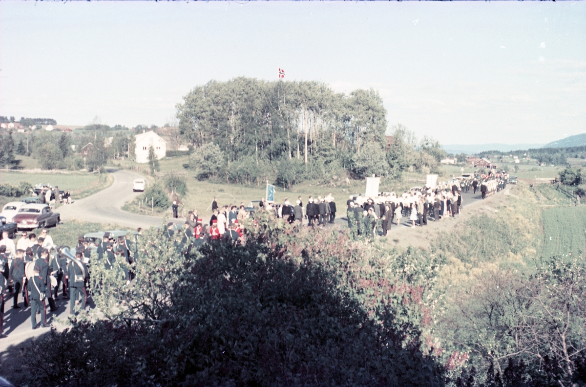 Serie på 16 bilder trolig fra Sangens og Musikkens Dag i Østre Toten, muligens 1961. Bildene er tatt i retning Brunsberg fra fotografens eiendom Odberg på Kraby, der forskjellige korps og kor deffilerer forbi.