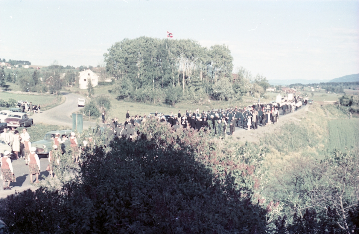 Serie på 16 bilder trolig fra Sangens og Musikkens Dag i Østre Toten, muligens 1961. Bildene er tatt i retning Brunsberg fra fotografens eiendom Odberg på Kraby, der forskjellige korps og kor deffilerer forbi.