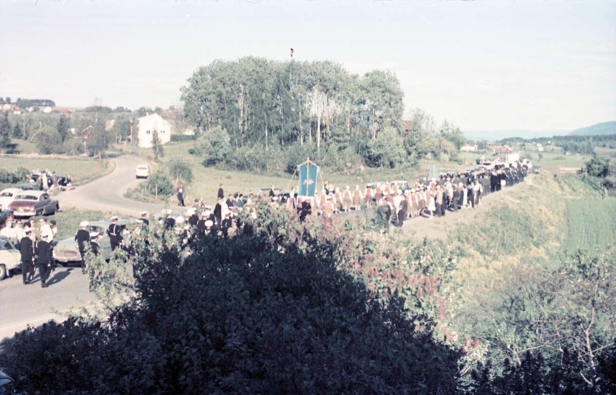 Serie på 16 bilder trolig fra Sangens og Musikkens Dag i Østre Toten, muligens 1961. Bildene er tatt i retning Brunsberg fra fotografens eiendom Odberg på Kraby, der forskjellige korps og kor deffilerer forbi.