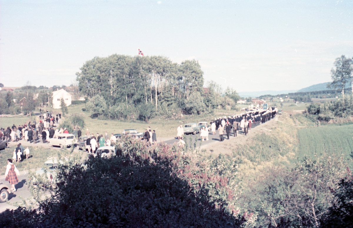 Serie på 16 bilder trolig fra Sangens og Musikkens Dag i Østre Toten, muligens 1961. Bildene er tatt i retning Brunsberg fra fotografens eiendom Odberg på Kraby, der forskjellige korps og kor deffilerer forbi.