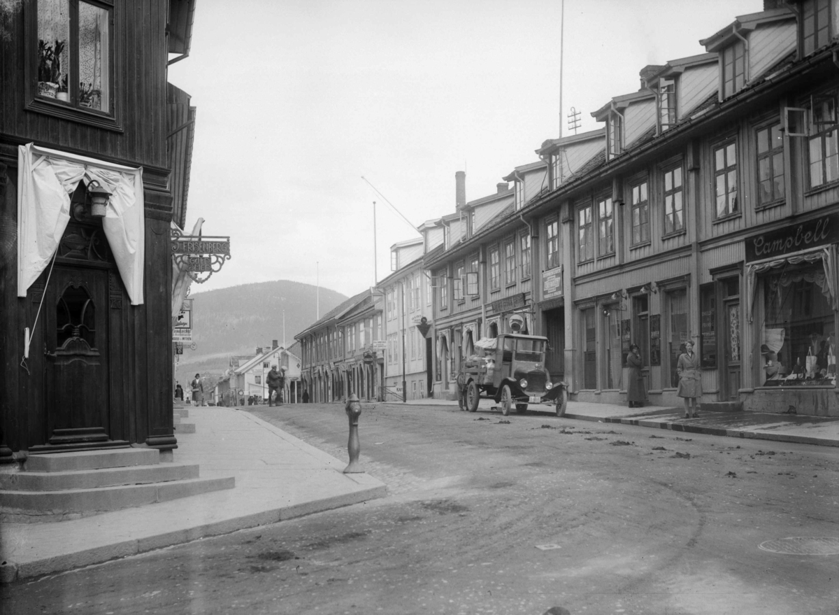 Storgata, Lillehammer. Frisenberg-hjørnet med Hellebergs forretning på østsiden. Lastebil D-140 parkert utenfor Helleberg