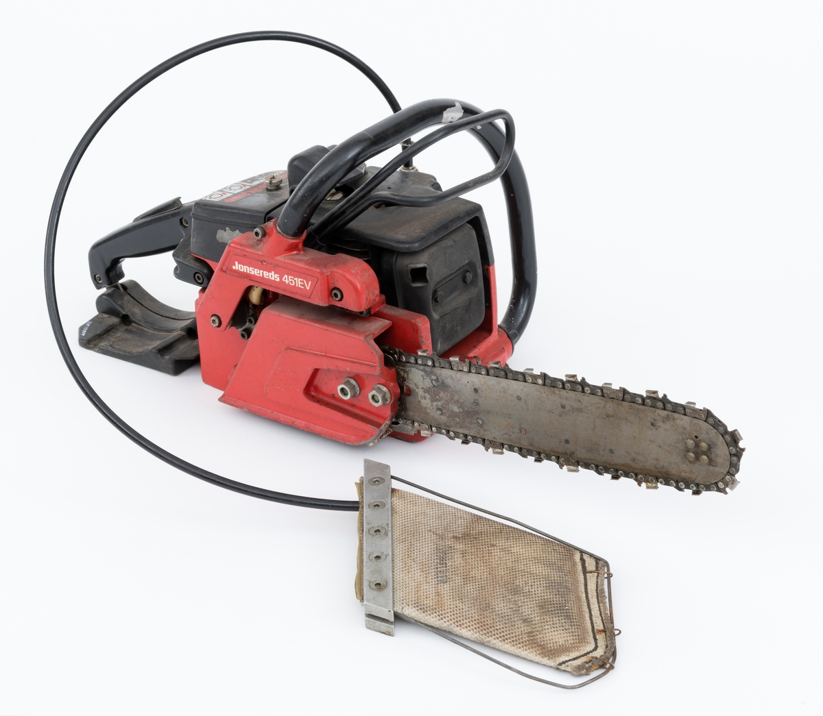 Motorsag av typen Jonsered 451EV med fellepute. Saga har påmontert sverd og sagkjede. Den ser for registrator ut til å være tilnærmet komplett og er videre blant annet utstyrt med elektronisk tenning,  avvibrerte håndtak, varme i håndtakene, vernebøyle og kjedebrems. 

Fellepute/presspute: Tilleggsutstyr påkoblet saga til hjelp under felling. Pressputa/felleputa kunne erstatte bruken av brytejern/fellespett. Utstyret består av en slange, hurtigkobling og pute. Puta har en tilnærmet rektangulær form, cirka 20 x 13 cm. Puta er laget av fiberarmert gummi. Selve puta er festet til en ramme bestående av to metallskinner i ene enden og en metalltråd som omslutter på tre sider. I nedre kant er puta festet til metalltråden med stålklemmer. Til puta er det koblet en svart slange med hurtigkobling. Disse enhetene har en lengde på cirka cirka 1 meter.  Slangen med hurtigkobling festes til en regulator på saga. Denne regulatoren er koblet til sagas motor inn ved starthuset. Det overføres "gass" fra sagas motor, sylinder, til puta som blåses opp som en ballong. Puta stikkes inn i felleskåret, slangen kobles på saga, og brukeren trykker på knappen slik at den fylles med "gass" og dermed hjelper treet i fallretningen.  Ut fra omtale i Jonsereds brosjyre skal puta ha en løftekraft på 4 tonn.  (Se vedlagte filer under fanen referanser.)


Det gjengis her noen tekniske spesifikasjoner fra salgsbrosjyra for Jonsered 451EV:  
(Se også vedlagt fil under fanen referanser som viser en allmenn beskrivelse av sagas spesifikasjoner. )
Sylindervolum/slagvolum: 44,3 kubikkcentimeter.
Kjedehastighet: cirka 20 meter per sekund.
Vekt: cirka 6,1 kg med sverd og kjede, også oppgitt til 7 kg (trolig vekt med fulle tanker)