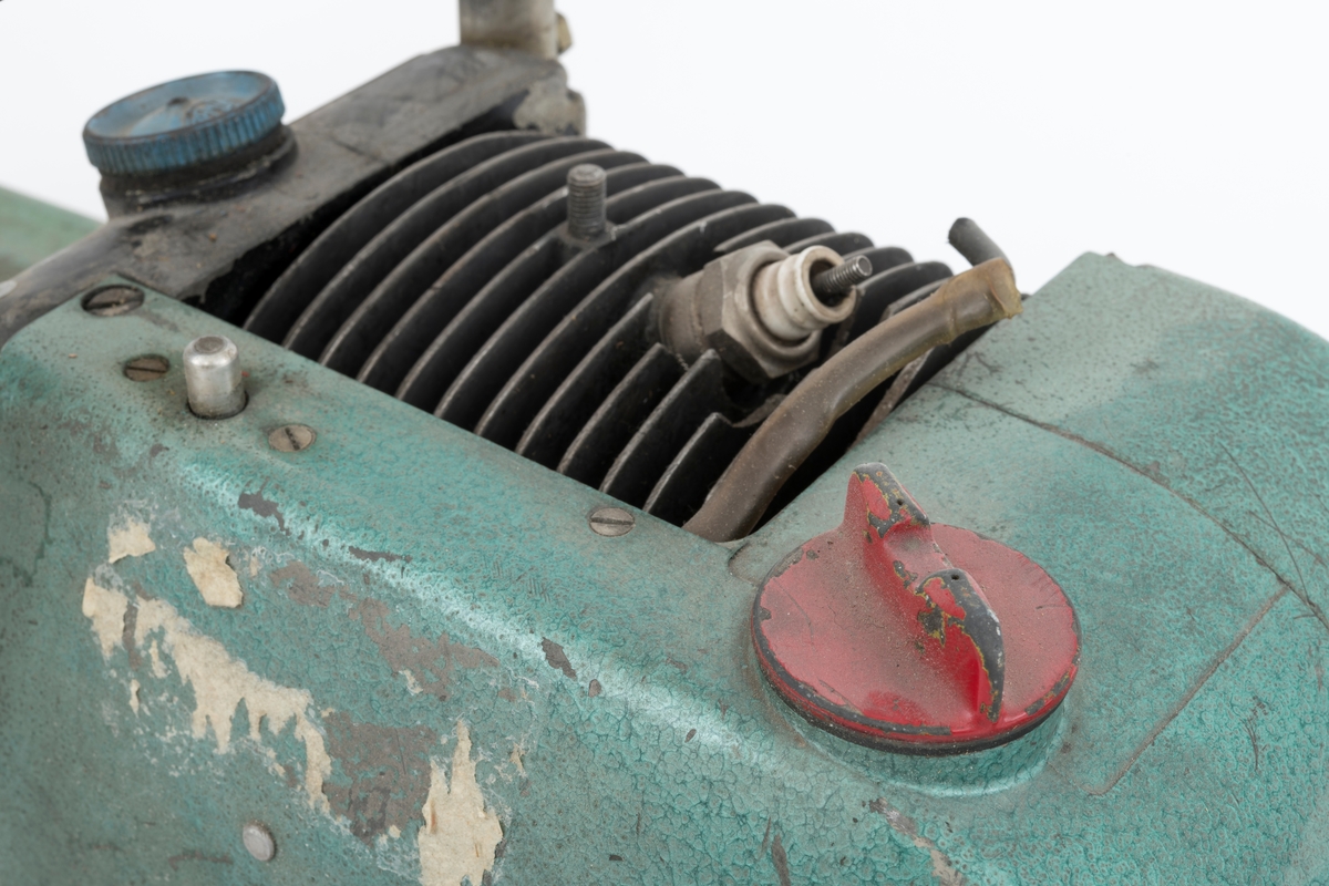 Motorsag av typen Jo-Bu D94 Tiger med påmontert barkeapparat (se beskrivelse nedenfor). Saga er også utsyrt med barkstøtte. Den fremre håndtaksbøylen er polstret med svart gummi rundt lettmetallrøret, cirka 11 centimenter langt felt, for å gi brukeren et bedre håndgrep. På toppen av sagkroppen, rett bak fremre håndtaksbøyle, gjenfinnes en kortslutningsbryter i blankt metall. For registrator ser saga komplett ut, kun tennpluggdeksel, tennplugghette og en skrue i startapparatet / starthuset mangler.  

Jo-Bu Tiger var den første direktedrevene saga fra Jo-Bu-fabrikken. Det vi si at kjedet settes i gang når motorens turtall overstiger et gitt antall omdreininger per minutt (2600). Når turtallet er under 2600 omdreininger står kjedet stille. (På tidligere Jo-Bu-modeller koblet man kjedet til og fra med en egen hendel.) Tiger var også den første Jo-Bu- modellen  med membranforgasser.  Dermed kunne den enkelt brukes til felling, kapping og kvisting uten at motoren stanset. (Flottørforgasseren, som var vanlig på de tidligere modellene, måtte stå i loddrett stilling for å fungere.) 

Særegent for denne saga (SJF.13864), er at sverd og kjede er byttet ut med et barkeapprat. Barkeapparatet som er montert på saga er av typen BRA-KAR (for mer informasjon om samme type barkeapparat se SJF.13709, store deler av beskrivelsesteksten er kopiert fra omtalen av denne gjenstanden.) Apparatet er en spesialkonstruert barkemaskin, barkeapparat, som kan kobles til motorsag eller drives med egen motor. Når appratet brukes på en motorsag byttes motorsagas sverd og kjede ut med barkeren (barkeapparatet), motorsagmotoren driver på den måte barkeren. Aggregatet /apparatet er festet til boltene i sverdfestet og skrudd fast med 2 muttre, en mutter mangler. 

Selve apparatet består av ei grønnlakkert ramme som i front er utstyrt med tre trinser, barketrinser. Trinsene er montert på akslinger som drives rundt av motorsagmotoren. Det er nødvendig med en egen tilkoplingsdel på motorsaga for å få barkeapparatet i drift. Registrator antar at kraften fra motosagmotoren overføres til barketrinsene via en tannhjulsveksel, snekkeveksel, som trinsene er direkte koblet til.  I bakkant av denne vekselen gjenfinnes en smørenippel for innpumping av fett. Apparatet har påmontert et stålhåndtak som er polstret med oransje gummi slik at brukeren får et mer behagelig grep.