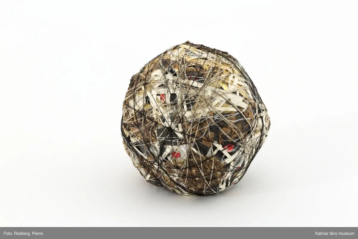 Tredimensionellt konstverk i form av ett klot, bestående av olika material och lindat.