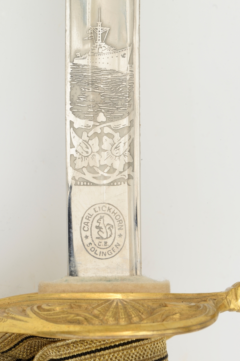 Norsk marinesabel Modell 1842. Feste i forgyllyt messing. Flat knapp med blomstermotiv. Nakkestykke merket "Lars Yggeseth"
Hvitt plastgrep med riller med snodd messingtråd i rillene. Gjennombrutt parerplate på utsiden med urent anker..Bakre parerstang svakt medbøyd og ender i en flattykt kule. Fremre parerstang går over i håndbøylen.
Gulltråde portepé flettet med alternativt svart/mørkeblått og gull.
Svakt krummet enegget klinge med rygg- og midtstillt blodrand. Klingen har etset dekor med moderne marinefartøy og kronet urent anker. Klimgen er merket med Carl Eichorns Solingenstempep i en oval rundt et ekorn.
Lærbalg med forgyllte messingbeslag. Munnblikket merket med norsk løve på forsiden og " Y " på baksiden. Midtbåndet er merket med kronet urent anker. Doppskoen har Neptuns tref ork og militære attributter.