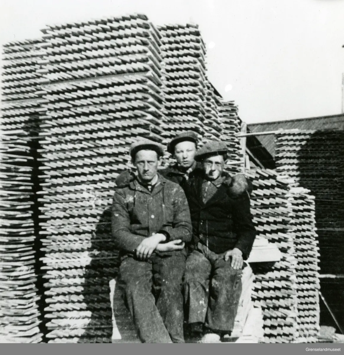 Motiv fra sagbruket på Jakobsnes. Foran materialstablene ser vi fra venstre: Oskar Johansen (Jakobsnes), Per Eikjok (Jakobsnes) og Leif Lorentzen (Kirkenes).