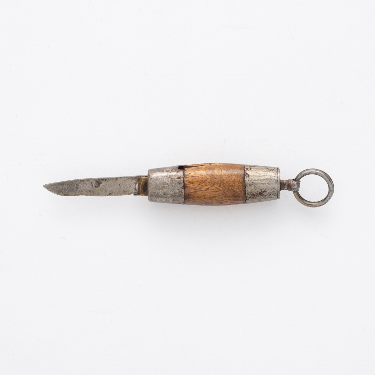 Liten sammenleggbar kniv i stål og messing med oval slire i tre og metall. Metallring til å trekke kniven ut av sliren.