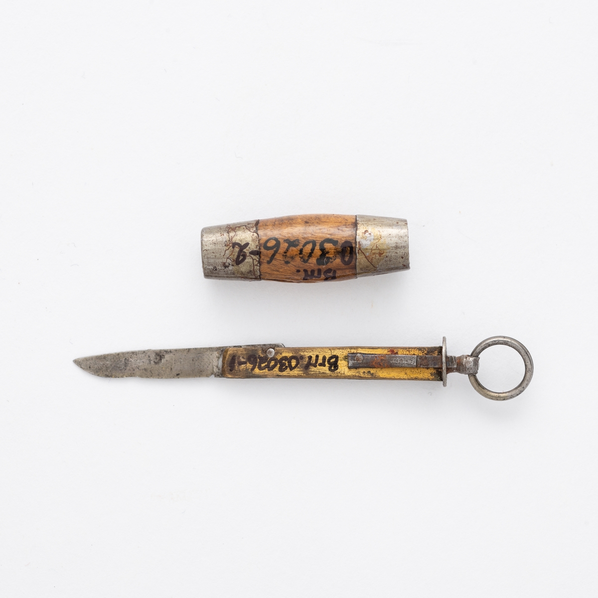 Liten sammenleggbar kniv i stål og messing med oval slire i tre og metall. Metallring til å trekke kniven ut av sliren.