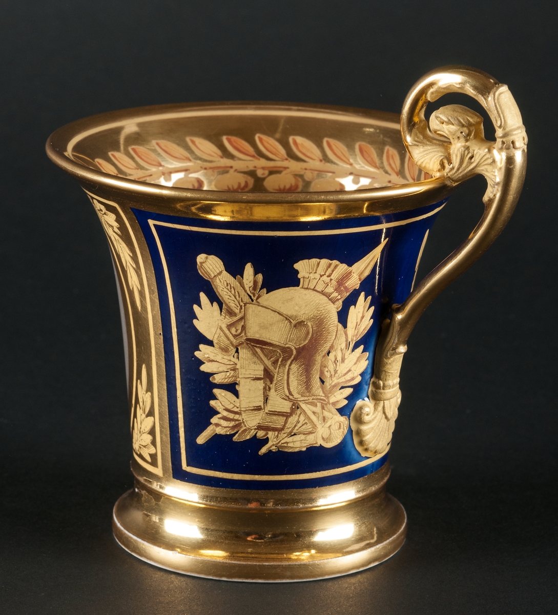 Karl XIII:S kopp.
Kopp med fat från Daite Freies i Paris, omkring 1800.
Koppens höjd 9.5 cm. Fatets diameter 16,5 cm.
Koppen bär på ena sidan Karl XIII:s bild och är på motstående sida dekorerad med ett par antika hjälmar.
Dekor i empirestil i guld och blått.
En grepe med örnhuvud och palmettdekor. Fatet är dekorerat med en eklövskrans.
