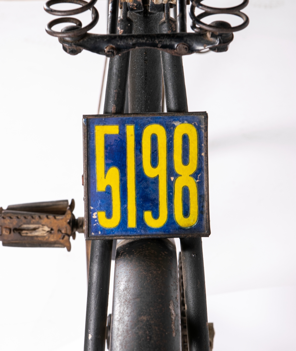 Cykel från 1800-talets slut.
Svartmålad. Gummidäck. Pakethållare i fram. Brun sadel av läder.
Den är tysk och är av märket Brennabor, modell No 1. Firman låg i Brandenburg.
Den är från sista årtiondena på 1800-talet.
Registreringsskyl i glas, nummer 5198.