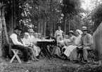 Christiane Liljefors med sönerna Roland, Alf och Ingemar tillsammans med andra barn och vuxna vid kaffebord ute i trädgård, sannolikt Sverige