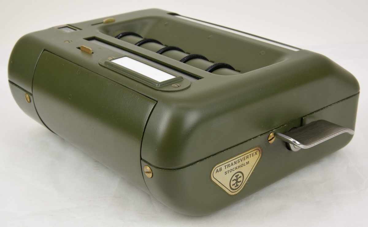 Krypteringsapparat (:1) med hölje av grönmålat aluminium i rundade former. Översidans framkant är lätt fasad och har ett avlångt fönster med alfabetet i över- och nederkant. Fönstret är till för att visa den alfabetsrulle som gav lösningen på kryptot. Under fönstret finns en svart skylt med vit text där siffrors bokstavskoder visas. På ovansidans mitt finns fem smala chifferhjul av svart bakelit i en försänkning. Hjulen är till för att ställa in chiffrets bokstäver som syns i ett fönster längst upp på apparatens ovansida. Till höger om chifferfönstret finns ett räkneverk med fyra siffror.

På apparatens framkant finns en skylt med M-nummer, serienummer och liknande och till höger ett vred av svart bakelit för att mata fram alfabetsrullen. På apparatens vänstra sida finns ett frammatningsvred av metall samt tillverkarens logotyp. På den högra sidan finns en lucka för alfabetsrullen och ett vred av bakelit för att ställa in chifferhjulaxeln. Baksidan har en större lucka för hålkortsplatsen och undersidan har små gummifötter samt en dekal med information om garantitid.

Till apparaten hör också en transportväska (:2) av formgjuten och genomfärgad gummi. Väskan är grön och har en vävd bärrem fäst med mässingsskruv. Locket är fäst med ett avlångt, nitat gångjärn och har ett låsspänne i mässing. På locket finns tre kronor och apparatens M-nummer i relief och på väskans undersida finns väskans M-nummer. Insidan av väskan är formad efter kryptoapparaten för att ge så mycket skydd som möjligt.

M-nummer: M 3858-301010
Tillverkningsnummer: 22749

Väskans M-nummer: M 7038-045010