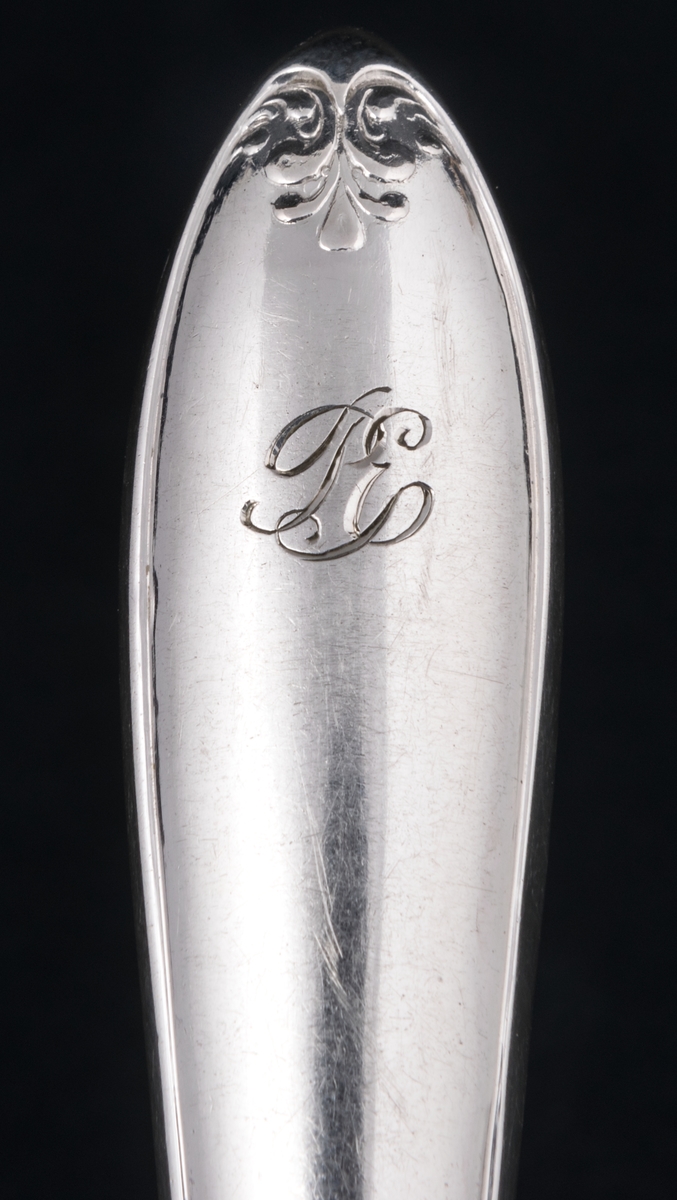 24 stycken matknivar av silver. Linjeartat ornament på skaftet. Gammelfransk modell.
Stämplad: GM F7 Kontrollstämpel, Sthlm.

Monogram: PE