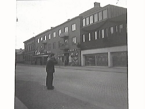 Stadsvy från Västra Vallgatan. Bilden tagen mot väster och visar södra delen av Domus samt biografen Capitol . 
Tidningsartikel: "De här herrarna som är betänkta på att kila 'raka spåret' över till Domus riskerar att bli bötfällda om de inte begagnar övergångsstället ca 20 meter längre bort". Publicerat i Hallandsposten 1967-01-05. Artikel i samband med bilden 6/3 1967.
