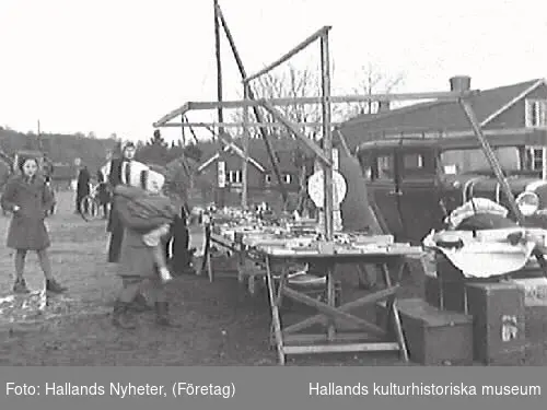 G25102 "Skällinge gamla marknadsplats ligger nu öde och tom."
G25104 "Ett par minnesgoda mannar, Edvard Nilsson, Attorp och Oscar Carlsson, Tågarp, vet mer om Skällinge marknad än någon annan." G25106 "En leksakshandlare - den ende på Skällinge marknad". 
Bilderna är publicerade i Hallands Nyheter 1947-12-17.