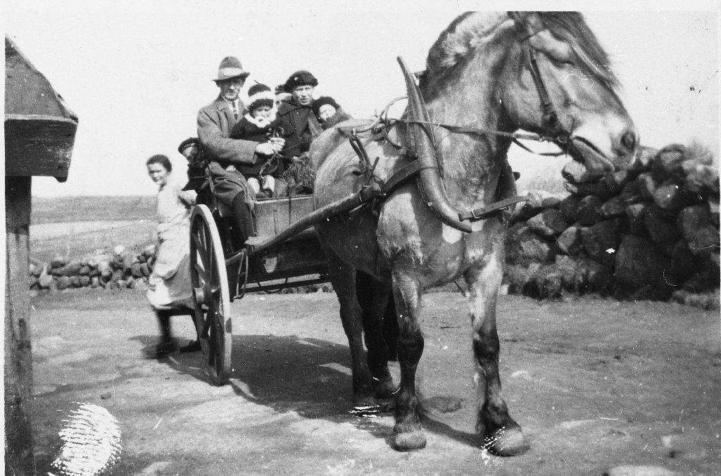 Torkel og Janna Gausland med 4 born kjører karjol. Barna er Magne Gausland, Ingrid Gausland, Alf Gausland og Trygve Gausland.Tenestejenta Berta Viken frå Bokn står bak. Biletet er teke i gardsrommet på Mossige i 1926.