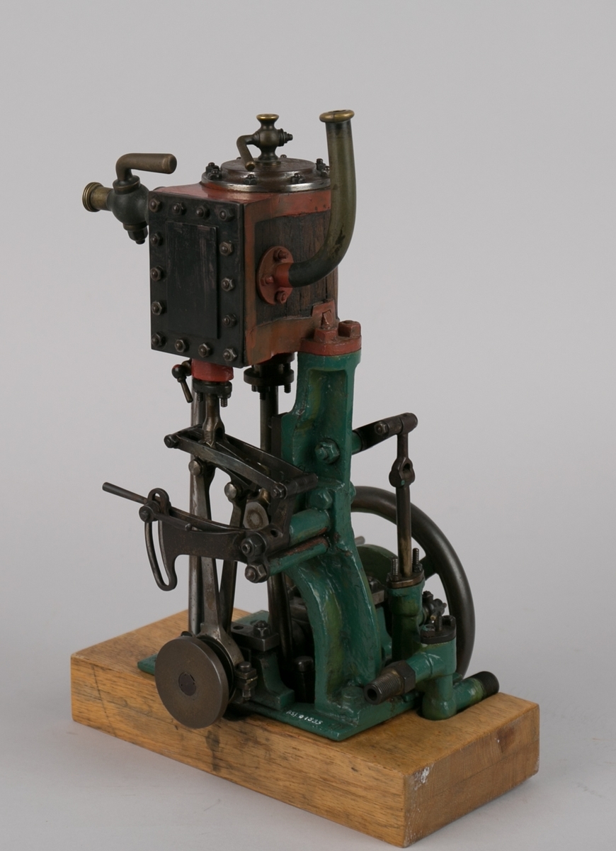 Dampmaskinmodell, 1- sylindret med oppstående kjele/dobbel plate av tre  og metall med dreiehjul på siden.  Montert på tresokkel.