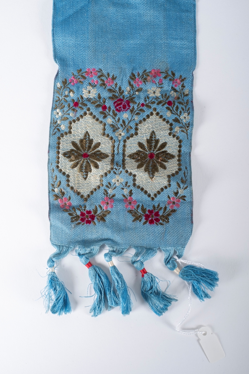 Blått skjerf med frynser og broderte blomster.