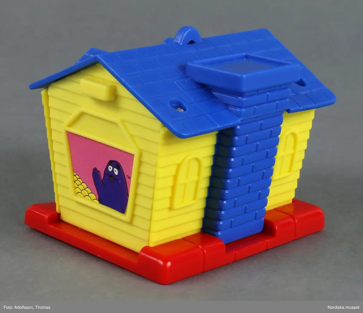 Leksakshus som föreställer en fruktaffär i miniatyr. Huset har flera fönster, dörr och skorsten. En clown, en maskerad pojke och ett lila spöke, tre figurer som ofta förekommer i McDonald's reklam, finns avbildade medan de plockar frukt. På taket finns en skylt med företagets namn och en hög med frukt. Metallskruvar håller ihop delarna.