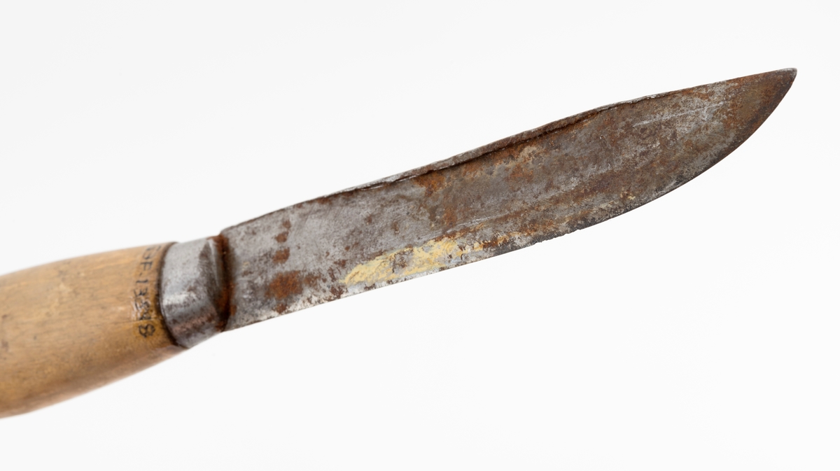 Tollekniv med slire, produsert av B. Knudsen på Ila i Trondheim. Kniven er 22,3 centimeter lang fra spissen av bladet til knappen i den bakre enden av skaftet. Bladet er 11,1 centimeter langt og snaut 2,1 centimeter bredt ved brystningen innerst mot skaftet. Bladet var opprinnelig snaut 3 millimeter tjukt, men bladryggen har slagmerker som har gjort den noe bredere. Sannsynligvis har dette skjedd fordi eieren har slått på knivnakken med et slagredskap for å kunne kløyve stikker som skulle brukes under opptenning. Den venstre sida av knivbladet bære smedstempelet «B. KNUDSEN  ILEN  TRONDHJEM». 

Kniven har et 10,8 centimeter langt treskaft med cirka 1 centimeter brede holker i begge ender. I den bakre enden er det en cirka 5 millimeter høy knopp med skråslipt endeflate. Treskaftet har en konveks form og et ovalt tverrsnitt. Midtpartiet måler 2,9 X 2,2 centimeter. Skaftet er ikke innsatt med noe fargestoff, men det kan ha vært oljet.

Slira er 18,2 centimeter lang, men har i tillegg en lærstropp for feste i en knapp i bukselinninga, slik at total lengde blir 24,6 centimeter. Sliras hoveddel er lagd av brunlig papp og holdes sammen av en søm langs det som var midtaksen av sliras bakside. Forsida av den delen av slira som omgav knivbladet har et siksak-mønster med litt skravur.

Knivmakerne Broder Knudsen (1886-1967) og Bård Knudsen bodde i Trondheim. Det er sannsynlig at en av disse har produsert denne kniven.