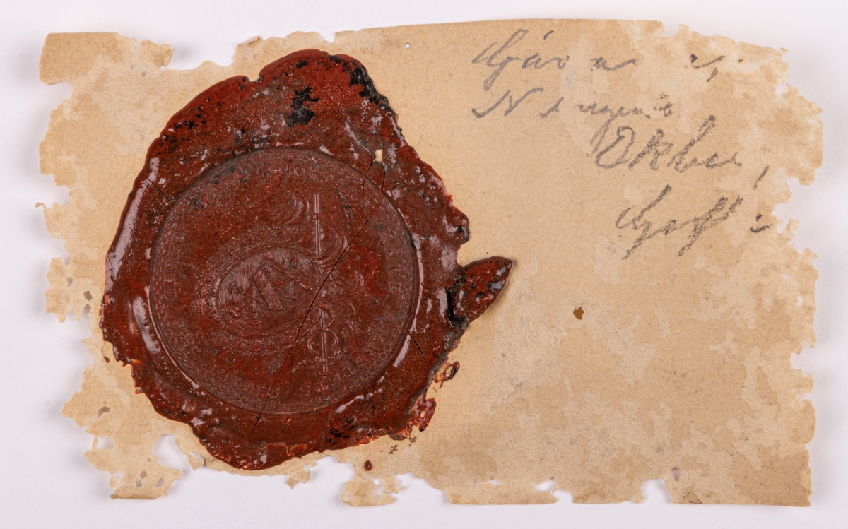 Gefle stads giördelmakareämbetes sigill, 1833. Fodral av sämskinn.

Lappkort.
Sigill, stamp av mässing, svarvat träskaft, av gröngul färg. Geflestads stads gördelmakare ämbets sigill 1833.