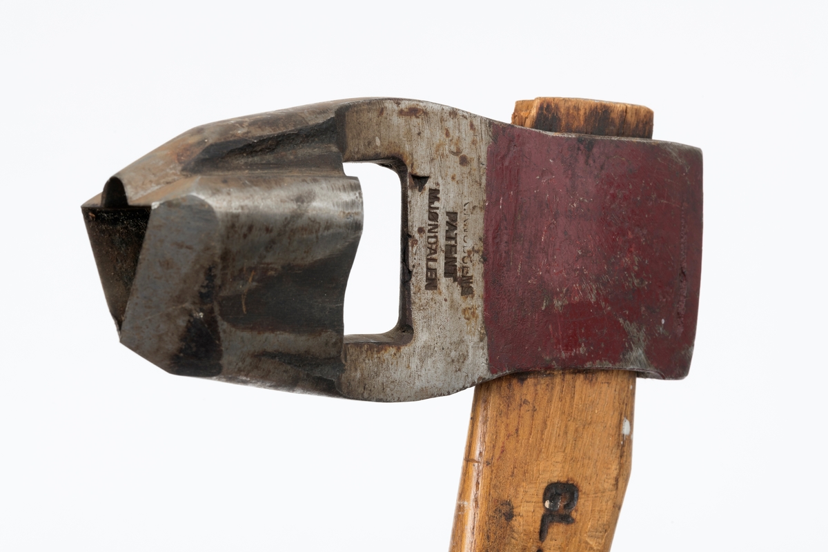 Øks - brukt til merking av fløtingstømmer i målings- og annammingsprosessen som foregikk langs vassdragene i overgangsfasen mellom vinter og vår, da tømmerstokkene etter måling formelt skiftet eier - fra skogeieren som hadde organisert hogst og framkjøring til sagbruk eller treforedlingsbedrift, som kjøpte tømmeret med sikte på videre bearbeiding til produkter som var salgbare på et større marked. 

Øksehodet (den smidde delen) er 16,3 centimeter høyt fra eggpartiet til nakken. Nakkedelen er 6,0 centimeter lang og om lag 2,6 centimeter bred. «Kjakene» - sideveggene rundt «øyet» (skafthullet) – er forholdsvis rette. På den nedre delen av øksebladet er det en U-formet utsparing, og til endestavene (Knudsen-smedene kalte dem «stabler») er det påsveiset en cirka 4,6 centimeter høy fasslipt, profilegget «sko». Eggprofilen er en trekant med en halvsirkelformet utbuktning på ei av sideflatene. Dette symbolet ble altså slått inn i yteveden på fløtingstømmeret, som tegn på hvem som eide stokkene. Den øvre delen av øksehodet er lakkert med rød lakk. På venstre side av dette øksebladet (sett i øksebrukerens perspektiv) finner vi smedstempelet «K. KNUDSEN  PATENT  MJØNDALEN». Smeden Karl Henrik Knudsen (1870-1956) tok patent på denne typen merkeøkser i 1908.

Øksa har et 60 centimeter langt og forholdsvis rett treskaft (sannsynligvis ask eller hickory). Som økseskaft flest er det bredest i høyderetningen og smalest i bredderetningen i den fremre enden, og mer rundovalt bakerst. Den fremre enden av skaftet er kilet med en trekile som skulle redusere faren for at øksa løsnet fra skaftet under merkingsarbeidet. Den venstre skaftsida har vært påført et navn ved hjelp av et svijernstempel.  Navnet er imidlertid forsøkt fjernet ved hjelp av ei rasp, antakelig fordi det firmaet som opprinnelig fikk tømmeret sitt merket med denne øksa ble avviklet, slik at merket muligens ble overtatt av en annen virksomhet. Det kan se ut til å ha stått «GL. KUR KOMPANI».

Litt generell informasjon om bruken av merkeøkser i skogbruket finnes under fanen «Opplysninger».