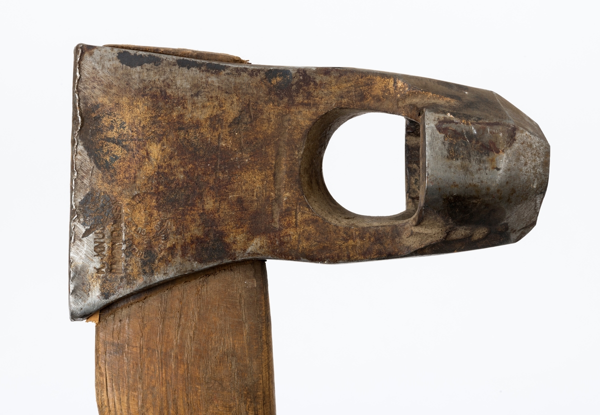 Øks - brukt til merking av fløtingstømmer i målings- og annammingsprosessen som foregikk langs vassdragene i overgangsfasen mellom vinter og vår, da tømmerstokkene etter måling formelt skiftet eier - fra skogeieren som hadde organisert hogst og framkjøring til sagbruk eller treforedlingsbedrift, som kjøpte tømmeret med sikte på videre bearbeiding til produkter som var salgbare på et større marked. 

Øksehodet (den smidde delen) er 13,5 centimeter høyt fra eggpartiet til nakken. Nakkedelen er 7,9 centimeter lang og om lag 2,6 centimeter bred bakerst, 2,2 centimeter i fronten. «Kjakene» - sideveggene rundt «øyet» (skafthullet) – smalner fra nakkepartiet mot den nedre delen av bladet. På den nedre delen av øksebladet er det en U-formet utsparing, og til endestavene (Knudsen-smedene kalte dem «stabler») er det påsveiset en cirka 3,7 centimeter høy fasslipt, profilegget «sko». Eggprofilen ble altså slått inn i yteveden på fløtingstømmeret, som tegn på hvem som eide stokkene. Øksehodet er, med unntak av den fasslipte eggen, lakkert med gulfarget lakk. Øverst på høyre side av øksehodet (sett i øksebrukerens perspektiv) finner vi stempelet «K. KNUDSEN MJØNDALEN» sammen med avbildninger av to medaljer denne smeden hadde oppnådd under vareutstillinger der han hadde vist produktene sine. Karl Henrik Knudsen (1870-1956) i Mjøndalen i Nedre Eiker patenterte denne typen merkeøkser i 1908.

Denne øksa har et drøyt 60,5 centimeter langt og forholdsvis rett treskaft (sannsynligvis ask eller hickory). Som økseskaft flest er det bredest i høyderetningen og smalest i bredderetningen i den fremre enden, og mer rundovalt bakerst. Den fremre enden av skaftet er kilet med en trekile som skulle redusere faren for at øksa løsnet fra skaftet under merkingsarbeidet.

Merkekart for Glomma knytter denne øksa til tømmer som ble annammet på vegne av firmaet Bay & Torp (merke nr. 223)

Litt generell informasjon om bruken av merkeøkser i skogbruket finnes under fanen «Opplysninger».