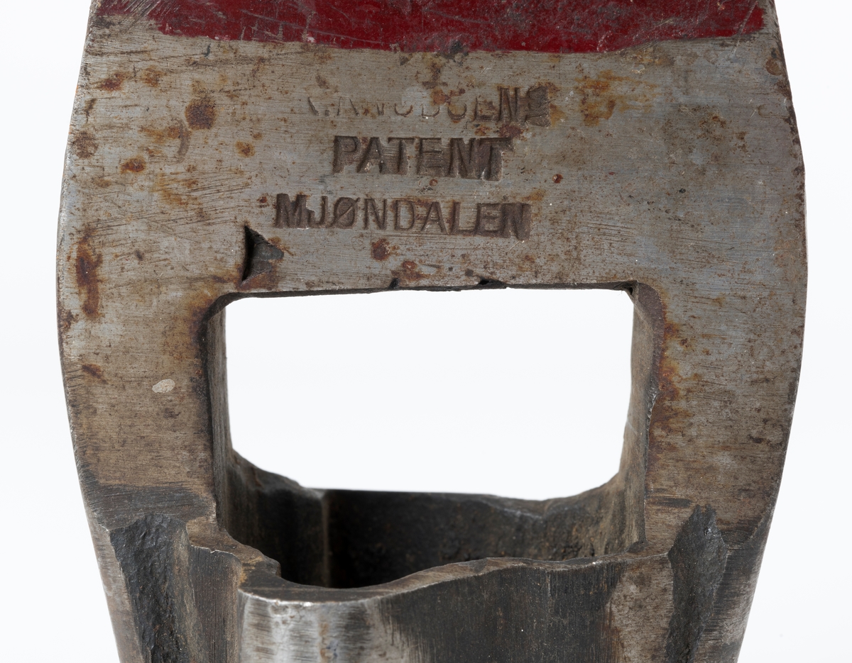 Øks - brukt til merking av fløtingstømmer i målings- og annammingsprosessen som foregikk langs vassdragene i overgangsfasen mellom vinter og vår, da tømmerstokkene etter måling formelt skiftet eier - fra skogeieren som hadde organisert hogst og framkjøring til sagbruk eller treforedlingsbedrift, som kjøpte tømmeret med sikte på videre bearbeiding til produkter som var salgbare på et større marked. 

Øksehodet (den smidde delen) er 16,3 centimeter høyt fra eggpartiet til nakken. Nakkedelen er 6,0 centimeter lang og om lag 2,6 centimeter bred. «Kjakene» - sideveggene rundt «øyet» (skafthullet) – er forholdsvis rette. På den nedre delen av øksebladet er det en U-formet utsparing, og til endestavene (Knudsen-smedene kalte dem «stabler») er det påsveiset en cirka 4,6 centimeter høy fasslipt, profilegget «sko». Eggprofilen er en trekant med en halvsirkelformet utbuktning på ei av sideflatene. Dette symbolet ble altså slått inn i yteveden på fløtingstømmeret, som tegn på hvem som eide stokkene. Den øvre delen av øksehodet er lakkert med rød lakk. På venstre side av dette øksebladet (sett i øksebrukerens perspektiv) finner vi smedstempelet «K. KNUDSEN  PATENT  MJØNDALEN». Smeden Karl Henrik Knudsen (1870-1956) tok patent på denne typen merkeøkser i 1908.

Øksa har et 60 centimeter langt og forholdsvis rett treskaft (sannsynligvis ask eller hickory). Som økseskaft flest er det bredest i høyderetningen og smalest i bredderetningen i den fremre enden, og mer rundovalt bakerst. Den fremre enden av skaftet er kilet med en trekile som skulle redusere faren for at øksa løsnet fra skaftet under merkingsarbeidet. Den venstre skaftsida har vært påført et navn ved hjelp av et svijernstempel.  Navnet er imidlertid forsøkt fjernet ved hjelp av ei rasp, antakelig fordi det firmaet som opprinnelig fikk tømmeret sitt merket med denne øksa ble avviklet, slik at merket muligens ble overtatt av en annen virksomhet. Det kan se ut til å ha stått «GL. KUR KOMPANI».

Litt generell informasjon om bruken av merkeøkser i skogbruket finnes under fanen «Opplysninger».