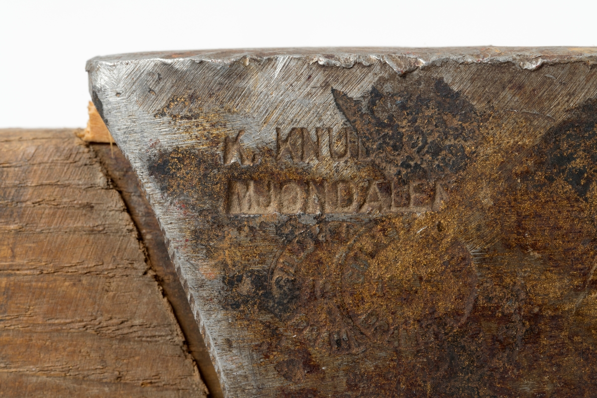 Øks - brukt til merking av fløtingstømmer i målings- og annammingsprosessen som foregikk langs vassdragene i overgangsfasen mellom vinter og vår, da tømmerstokkene etter måling formelt skiftet eier - fra skogeieren som hadde organisert hogst og framkjøring til sagbruk eller treforedlingsbedrift, som kjøpte tømmeret med sikte på videre bearbeiding til produkter som var salgbare på et større marked. 

Øksehodet (den smidde delen) er 13,5 centimeter høyt fra eggpartiet til nakken. Nakkedelen er 7,9 centimeter lang og om lag 2,6 centimeter bred bakerst, 2,2 centimeter i fronten. «Kjakene» - sideveggene rundt «øyet» (skafthullet) – smalner fra nakkepartiet mot den nedre delen av bladet. På den nedre delen av øksebladet er det en U-formet utsparing, og til endestavene (Knudsen-smedene kalte dem «stabler») er det påsveiset en cirka 3,7 centimeter høy fasslipt, profilegget «sko». Eggprofilen ble altså slått inn i yteveden på fløtingstømmeret, som tegn på hvem som eide stokkene. Øksehodet er, med unntak av den fasslipte eggen, lakkert med gulfarget lakk. Øverst på høyre side av øksehodet (sett i øksebrukerens perspektiv) finner vi stempelet «K. KNUDSEN MJØNDALEN» sammen med avbildninger av to medaljer denne smeden hadde oppnådd under vareutstillinger der han hadde vist produktene sine. Karl Henrik Knudsen (1870-1956) i Mjøndalen i Nedre Eiker patenterte denne typen merkeøkser i 1908.

Denne øksa har et drøyt 60,5 centimeter langt og forholdsvis rett treskaft (sannsynligvis ask eller hickory). Som økseskaft flest er det bredest i høyderetningen og smalest i bredderetningen i den fremre enden, og mer rundovalt bakerst. Den fremre enden av skaftet er kilet med en trekile som skulle redusere faren for at øksa løsnet fra skaftet under merkingsarbeidet.

Merkekart for Glomma knytter denne øksa til tømmer som ble annammet på vegne av firmaet Bay & Torp (merke nr. 223)

Litt generell informasjon om bruken av merkeøkser i skogbruket finnes under fanen «Opplysninger».