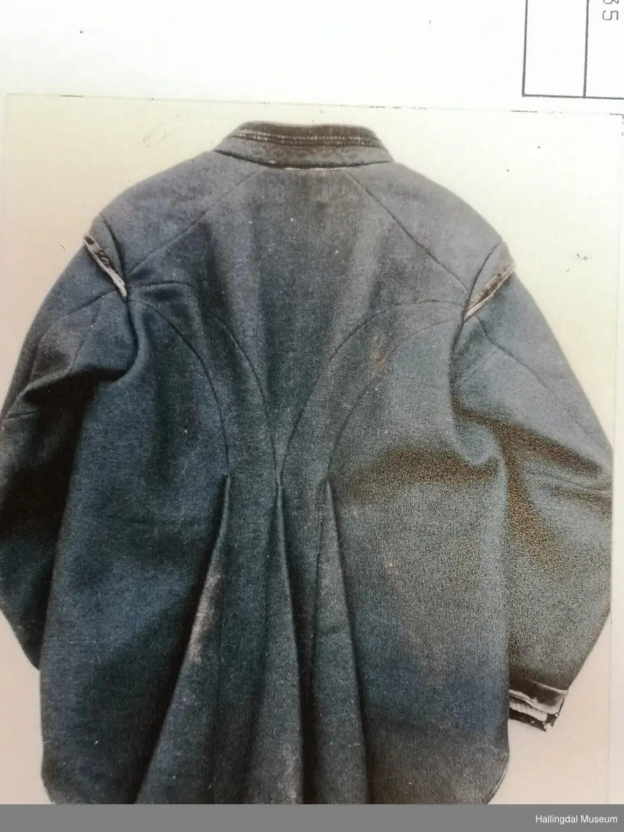 Fra bunadsregistreringene i Flå 1985: 
" Ullstoff, bomullsstoff, fløyelsstoff, vevd, sydd.
Sølvknappene festet med band-fleskereim. (griseskinn).  Trøya, fiskekjølkjen er sydd av svart heimevevd vadmel.  Ryggen er satt sammen av 3 stoffstykker + 3 innfelte folder nederst i ryggen.  Framstykket går bakover inntil ytterste foldene.  Foldene er 19 cm breie nederst, 40 cm høye, ender i en spiss.  5 stoffstykker i venstre erme, 4 stoffstykker i høgre.  Splitt fremst på ermene.  Et lite stoffstykke kanta med fløyel på skuldrene-ermbryninger.  Avrunda hjørner nederst på framstykka.  Rundt hele trøya, for på ermene og under kragen er det kanta med svart fløyel i ulike bredder.  6 knapper i filigrans på hver side. 2,6 cm i diam, hemper at kobber, såkalt Udalsknapp, smeden bodde i Udalen, husmannsplass under Aavestrud.  Sølvknapper-1,8 cm diam fremst på ermene.  Trøya, fiskekjølkjen er fora med tynt bomullsstoff, grått m/ kvite striper.  Foret går bare 40 cm ned.  På kragen er det stikninger i buer og spisser.  Trøya er delvis sydd m/ hand, noe med maskin.  15/10-85 Marit B. Jorde" Sølvknappene ble tatt av trøya av eieren før den ble levert inn til Hallingdal Museum. Silkevest HFN 13814 kommer også fra Ole Aavestrud.