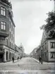 Skolgatan mot väster från Kyrkogatan i Jönköping. Till vänster, Kyrkogatan 12, ett av de äldsta tegelhusen i staden, ritat av stadsarkitekt Fredrik Sundbärg år 1897. Till höger ses Ljungs Platsanskaffningsbyrå.