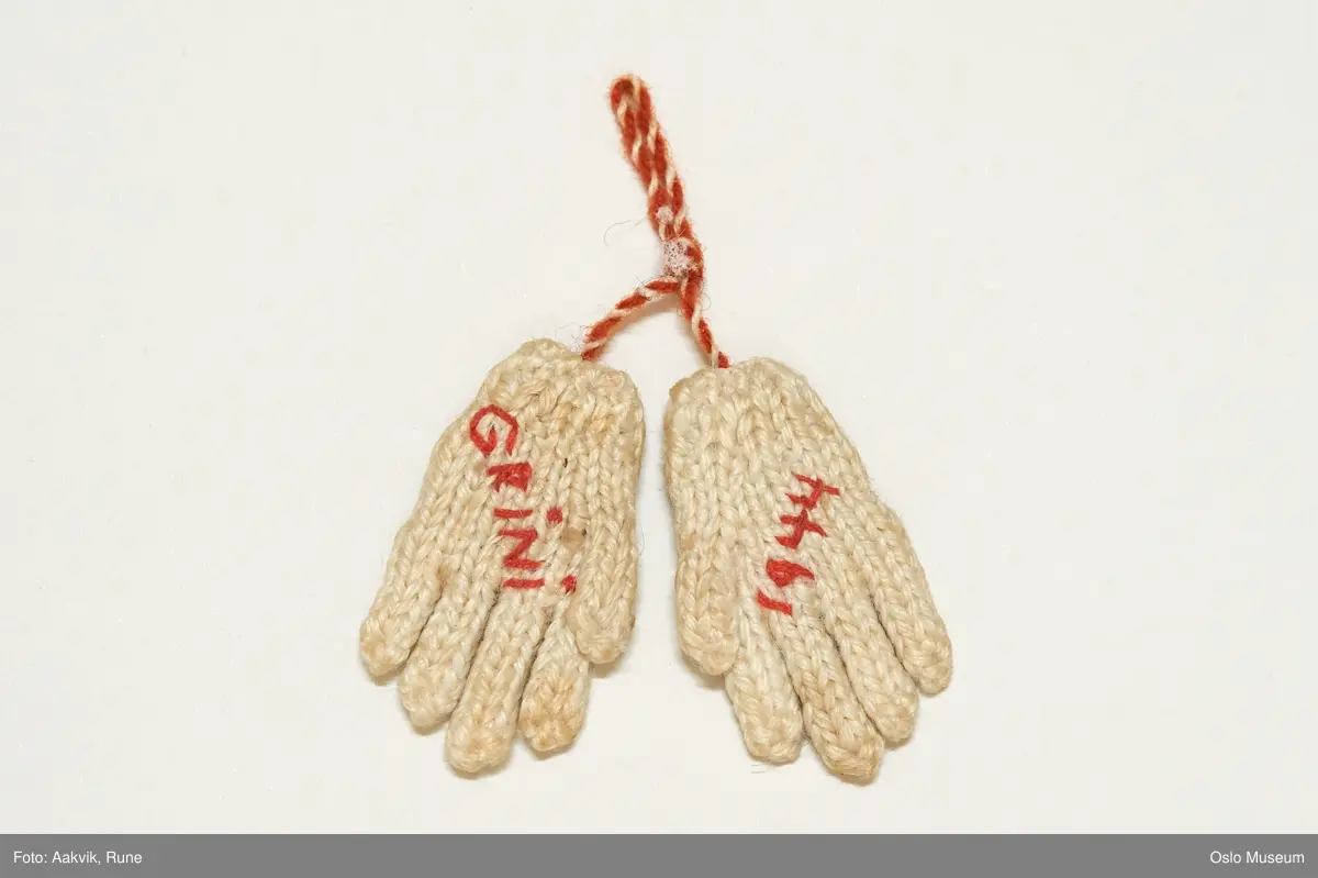 bittesmå hvite strikket votter med rosemønster og tekst