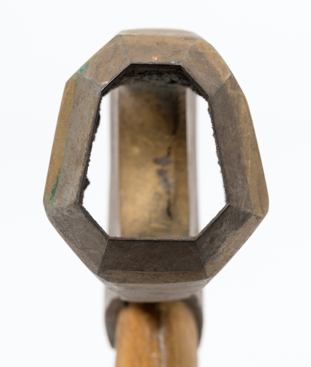 Øks - brukt til merking av fløtingstømmer i målings- og annammingsprosessen som foregikk langs vassdragene i overgangsfasen mellom vinter og vår, da tømmerstokkene etter måling formelt skiftet eier - fra skogeieren som hadde organisert hogst og framkjøring til sagbruk eller treforedlingsbedrift, som kjøpte tømmeret med sikte på videre bearbeiding til produkter som var salgbare på et større marked. 

Øksehodet (den smidde delen) er 13,1 centimeter høyt fra eggpartiet til nakken. Nakkedelen er 8,2 centimeter lang og om lag 2,5 centimeter bred bakerst, 2,2 centimeter i fronten. «Kjakene» - sideveggene rundt «øyet» (skafthullet) – smalner fra nakkepartiet mot den nedre delen av bladet. På den nedre delen av øksebladet er det en U-formet utsparing, og til endestavene (Knudsen-smedene kalte dem «stabler») er det påsveiset en cirka 3,8 centimeter høy fasslipt, profilegget «sko». Eggprofilen er en noe avlang åttekant (oktogon). Dette symbolet ble altså slått inn i yteveden på fløtingstømmeret, som tegn på hvem som eide stokkene. Øksehodet er, med unntak av den fasslipte eggen, lakkert med gulfarget lakk. Denne øksa har ikke noe smedstempel, men form og overflatebehandling tyder på at den er produsert av smeden Karl Henrik Knudsen (1870-1956) i Mjøndalen i Nedre Eiker.

Denne øksa har et 61 centimeter langt og forholdsvis rett treskaft (sannsynligvis ask eller hickory). Som økseskaft flest er det bredest i høyderetningen og smalest i bredderetningen i den fremre enden, og mer rundovalt bakerst. Den fremre enden av skaftet er kilet med en trekile som skulle redusere faren for at øksa løsnet fra skaftet under merkingsarbeidet.

Ifølge «Merkekart 1953 for Glommen» (gjengitt i Julius Nygaards skogalmanakk for 1954) ble dette merket brukt av Fetsund lenser i Glommavassdraget (jfr. merke nr. 35).

Litt generell informasjon om bruken av merkeøkser i skogbruket finnes under fanen «Opplysninger».