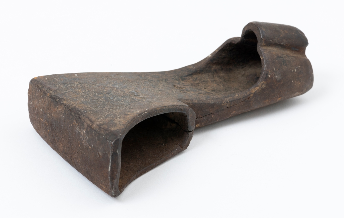 Øksehode – brukt til merking av fløtingstømmer i målings- og annammingsprosessen som foregikk langs vassdragene i overgangsfasen mellom vinter og vår, da tømmerstokkene etter måling formelt skiftet eier – fra skogeieren som hadde organisert hogst og framkjøring til sagbruk eller treforedlingsbedrift, som kjøpte tømmeret med sikte på videre bearbeiding til produkter som var salgbare på et større marked. 

Øksehodet (den smidde delen) er snaut 14,3 centimeter høyt fra eggpartiet til nakken. Nakkedelen er 9,0 centimeter lang og om lag 3,1 centimeter bred. «Kjakene» – sideveggene rundt «øyet» (skafthullet) – smalner mot den nedre delen av bladet. Det er en sprekk i godset i underkant av øyet. Nederst på bladet er det utsmidd en drøyt 3 centimeter høy fasslipt, profilegget «sko» (målet er tatt i ytterkant, der denne komponenten er smalest). Eggprofilen er formet som omrisset av en fugl med utspente vinger. Dette symbolet ble altså slått inn i yteveden på fløtingstømmeret, som tegn på hvem som eide stokkene. Øksehodet har ikke noe synlig smedstempel. Stålet er noe rustent. Bokstavene «OT» - antakelig smedens initialer - er antakelig smedens initialer.

Dette øksemerket ble ifølge merkekart for Glomma fra 1921 bruk til tømmer som ble innkjøpt på vegne av Lillestrøms Cellulosefabrik, en treforedlingsbedrift som var i virksomhet fra 1908 til 1943 (de første åra under navnet «Lillestrøm Sulfitfabrik»).

Litt generell informasjon om bruken av merkeøkser i skogbruket finnes under fanen «Opplysninger».