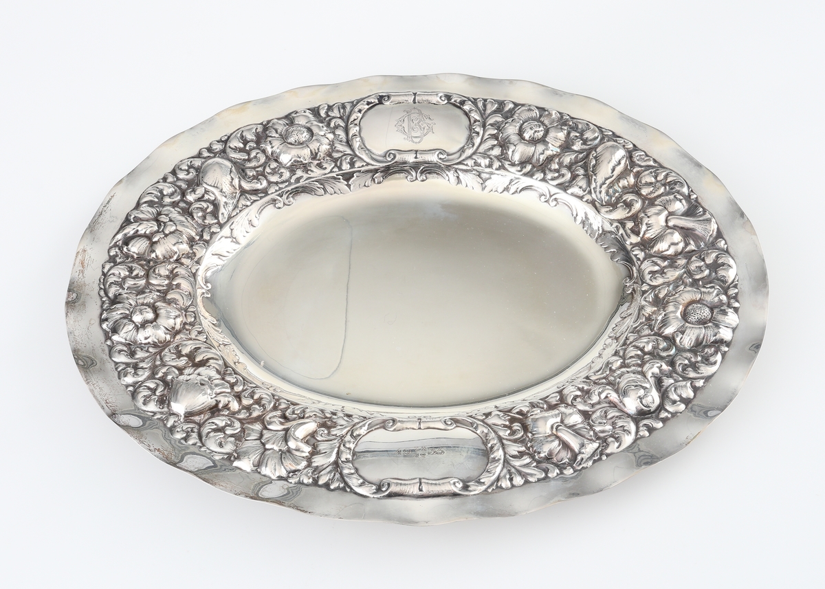 Fat av silver.
Ovalt prydnadsfat, med pressad dekor i hög relief på brättet, bestående av blommor och bladornament. Brättet är försett med två bekransade ramar, i den övre kanten är ett graverat monogram: "G B". I den undre kanten står: "19 22/12 35". På fatets baksida finns följande text: "Till Gunnar Borner på 50-årsdagen från kollegor i Kronobergs län". 
Stämplar på brättets undersida.

Inskrivet i huvudbok 1962