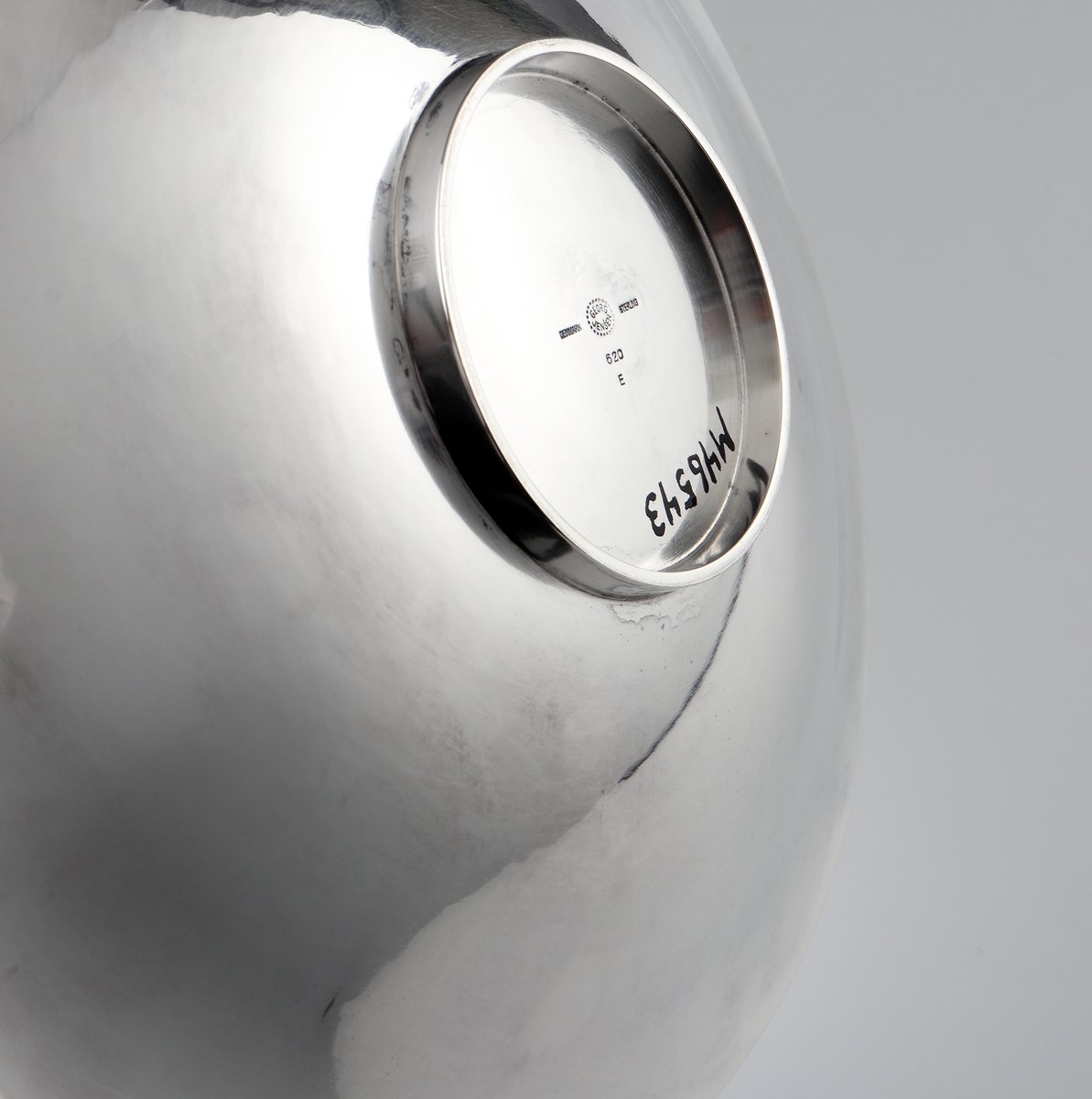 Fat av silver.
Rund, slät modell på låg, rund fot. På foten är graverat: "Fra Holmegaards Glasverk 8-9-1962". 
Inuti foten finns tillverkarstämpel m.m.

Inskrivet i huvudbok 1983.