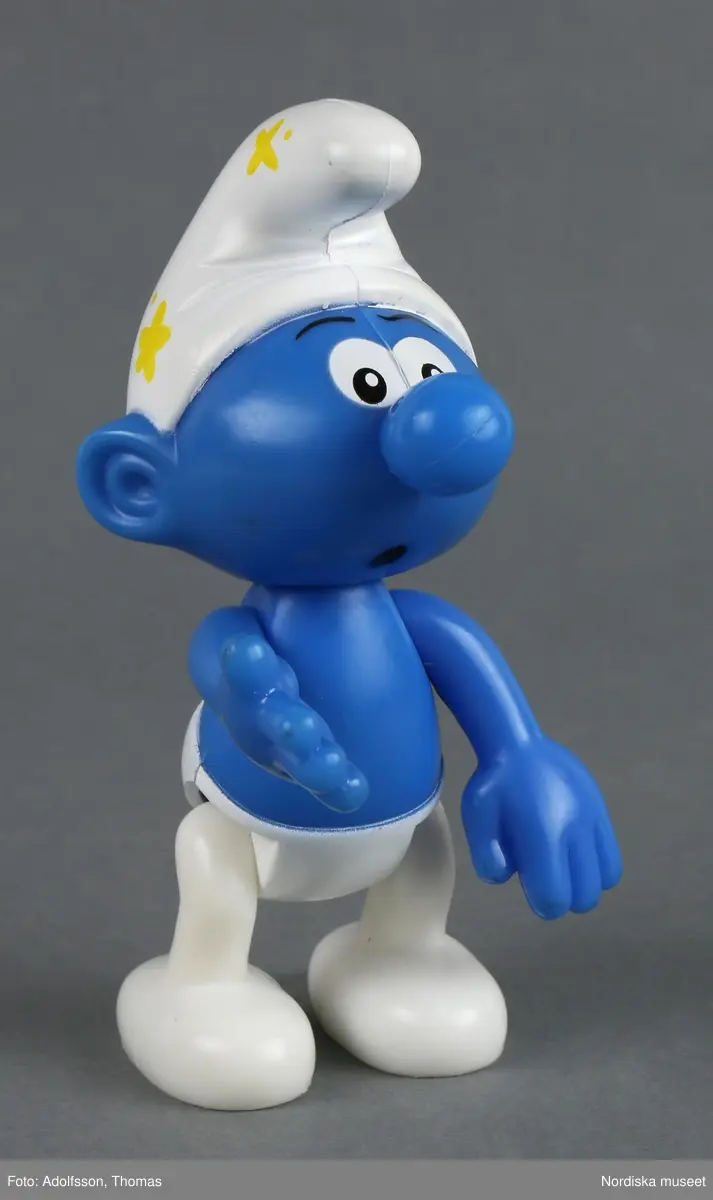Tomteliknande figur som kallas Smurf, med blå kropp, vit luva och vita byxor. Rörliga armar och ben.