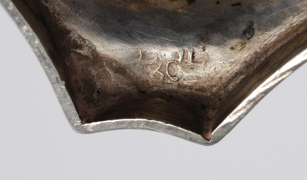 S.k. supkalk av silver, med ben och fot. 
Graverat mönster på skålens kant och på foten. Invändigt är cuppan förgylld. Foten är åttkantig. 
Stämplar (deformerade, svårtydda) i botten. 

Inskrivet i huvudkatalogen 1963.