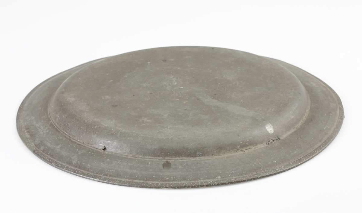 Fat av tenn.
Runt, hamrat stekfat. Brämen avslutas med rundstav. På brämens ytterkant finns två graverade monogram inom en bård: "S.O.S., K.A.D., 1822". På brämens undersida finns graverat ägarinitialer: "I.V.R.". Stämplar på brämens översida.

Inskrivet i huvudbok 1886.