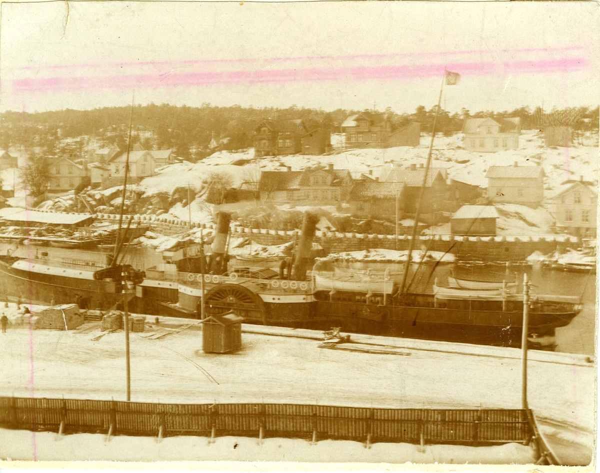 Hjuldamper
(Det Forenede Dampskibsselskabs "H. P. Prior", bygget ved Burmeister & Wain i København i 1878),
Glomma,
Vesterelven, Kråkerøy (over elven), Bjølstadfjellet,
Verkstedveien (Kråkerøy),
Thorbjørnsens skipsopphugging (på Kråkerøysiden, lavt tak, tv),
Bankbrygga (Kirkebrygga) (i forgrunnen).,
