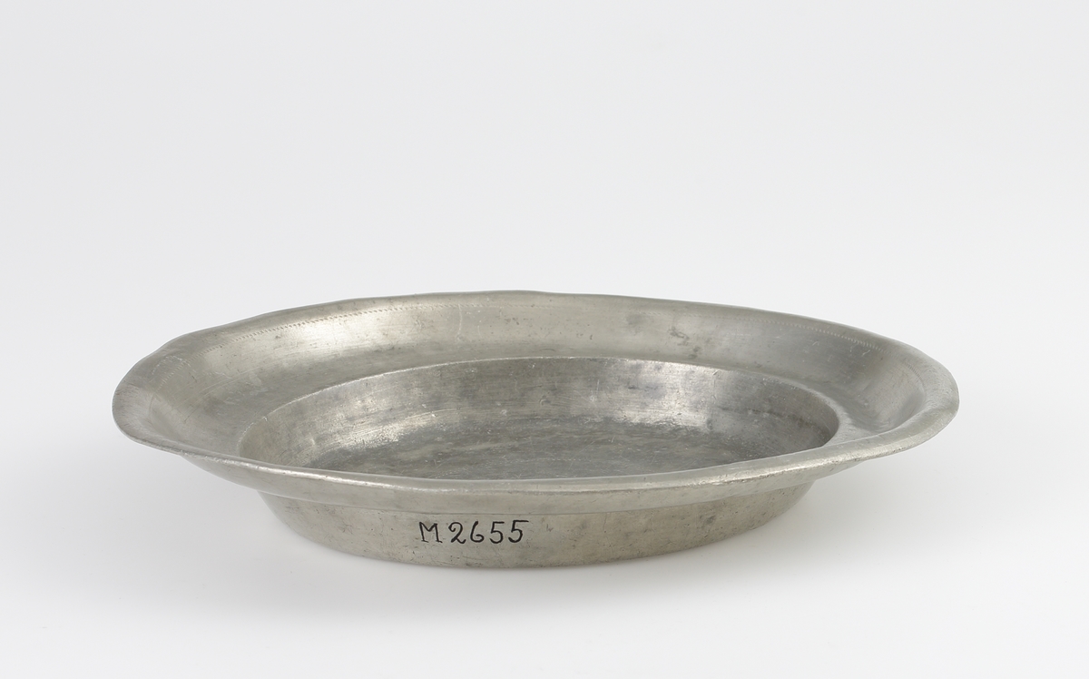 Fat av tenn. Rund, djup modell med uppsvängd bräm, dekorerad med en svarvad linje. 
Ägarinitialer på bottnens utsida: "LSD". Stämplar (mycket nötta och svårtydda) i fatets spegel.

Inskrivet i huvudbok 1903.