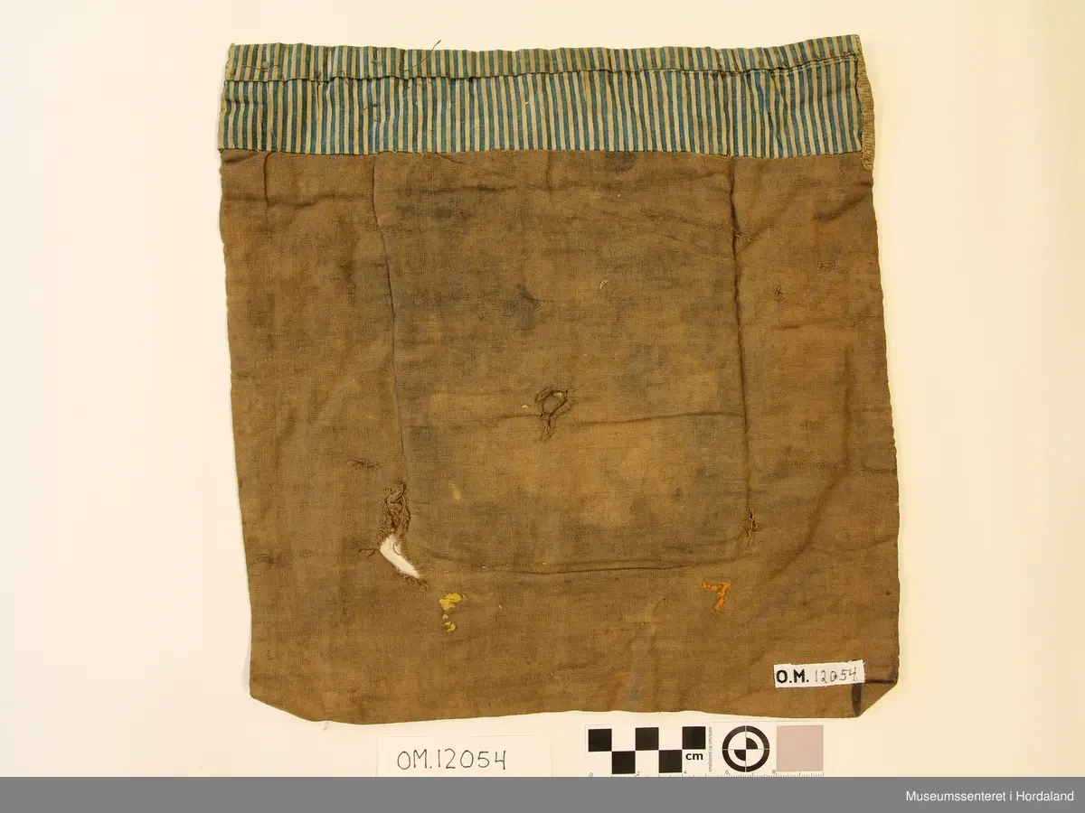 Hovudmotivet på bringeduken er brodert i krossting på stramei med ullgarn, det kvite er brodert med bomullsgarn.  Oppe er det ei smal borde i smøyg.Ovanfor der att er det ei borde klipt av eit raudt trykt stoff (Kattuntrykk). Dette er montert på eit bakstykke av bomullslerret som kanskje har vore kvitt, er brunt no.. Under hovudmotivet er det ein liten brunrutete trekant i eit anna bomullstoff. På kvar side av denne trekanten står initialane, M til venstre og T til høgre. Øvst oppe er det ein kant av eit blå-  og kvitstripete bomullststoff som er bretta rundt og går nedatt på baksida. Rett nedanfor det er det ein anna stoff.